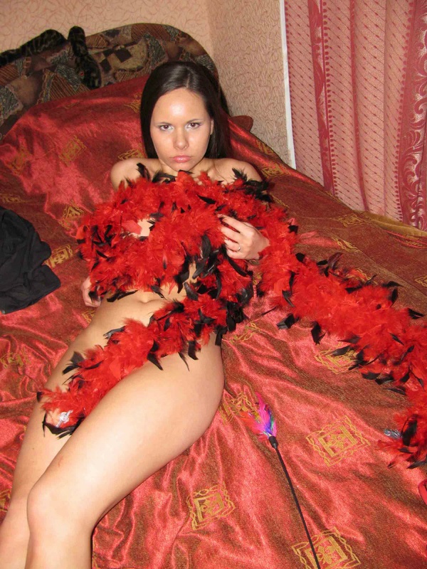 Девушка с отличной фигуркой на кровати в красных перьвях 4 фото