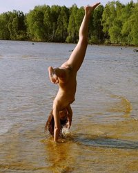 Эротичная гимнасточка голышом тренируется на речном берегу 12 фотография