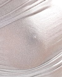 Кудрявая сучка позирует на диване в серебристом платье 2 фотография