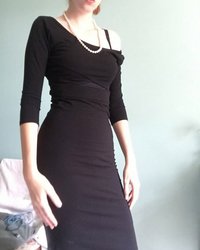 Длинноногая красотка в черном платье светит обнаженным телом 1 фотография