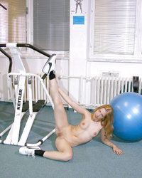 Худощавая спортсменка показывает обнаженное тело возле тренажера 14 фотография